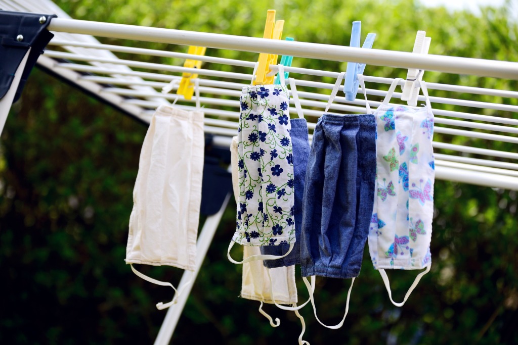 Cloth face masks with blue and floral patterns hanging from a washing line